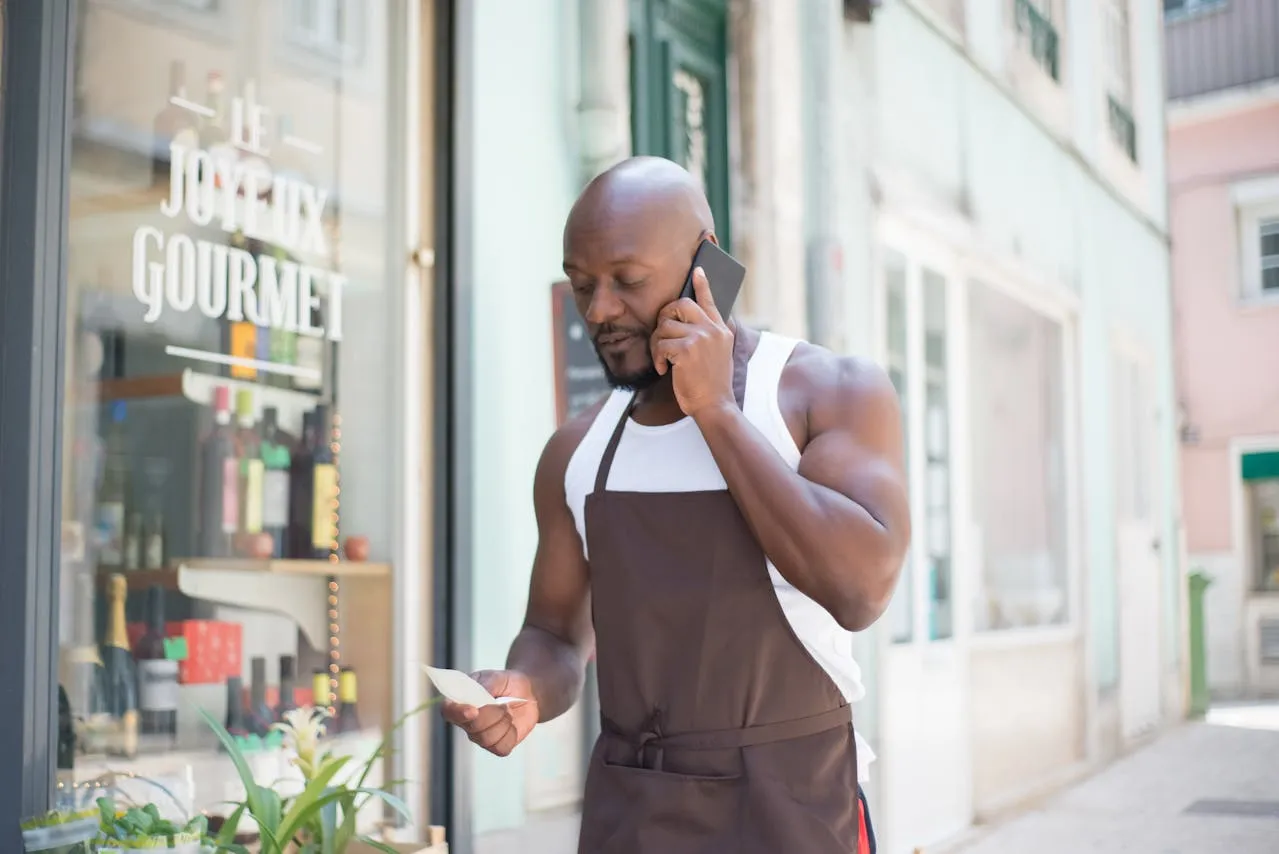 A business owner on a phone call with list in hand outside the restaurant
